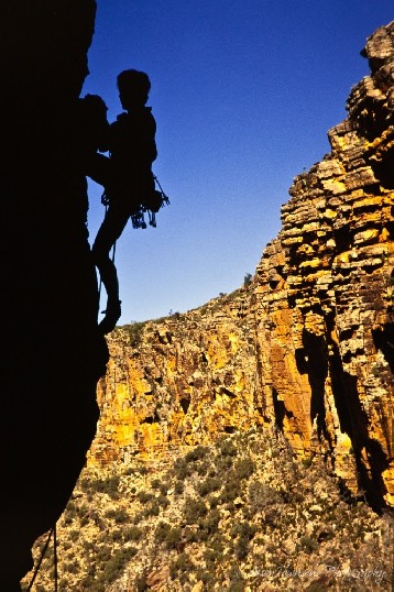A climber in shadow scales the cliffs of Wilpena pound.