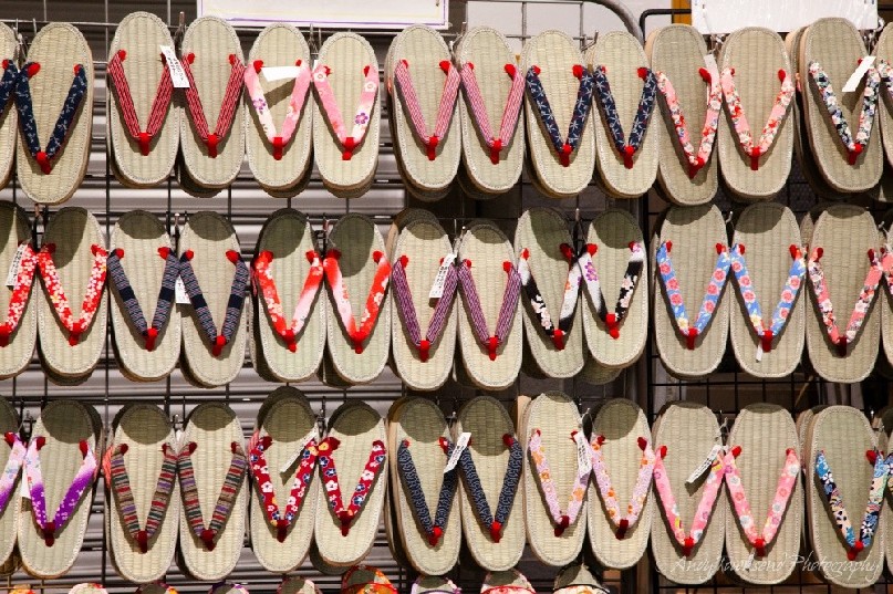 Lines of Geta sandals with colourful straps adorn this shop wall.