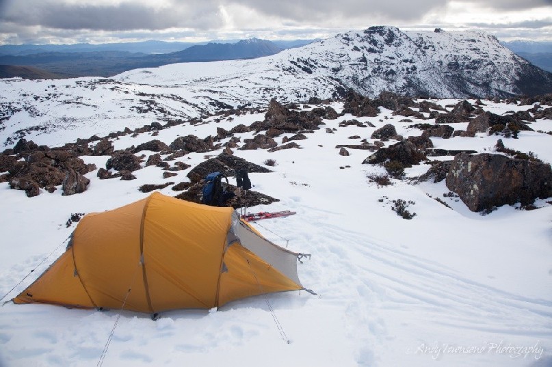 A yellow tent perched on the Rodway ridge overlooking Naturalist Peak and Mt Field West.