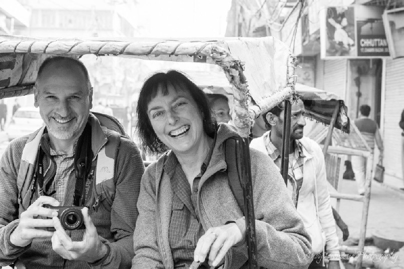 A man and women laughing after riding a motorised rickshaw along Delhi streets.