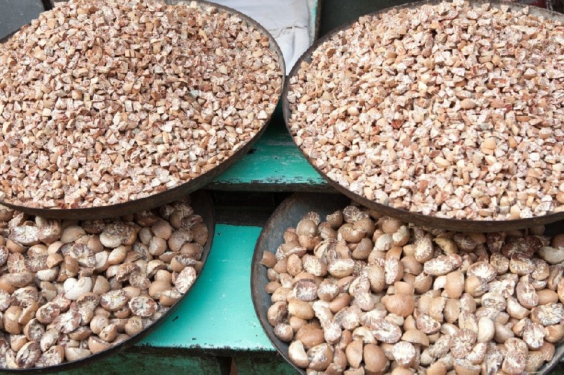 Different gardes of betel nuts in large metal bowls at a wholesale vegetable market in Delhi.