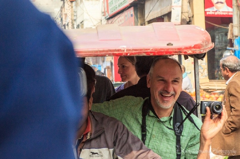 A man smiling films from a motorised rickshaw in Old Delhi.