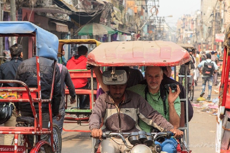 A man concentrates while filming the streets in a motorised rickshaw.
