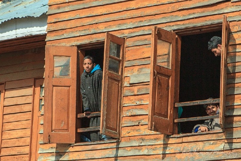 Three young Kashmiri boys framed in upper level windows at Babaeshi.