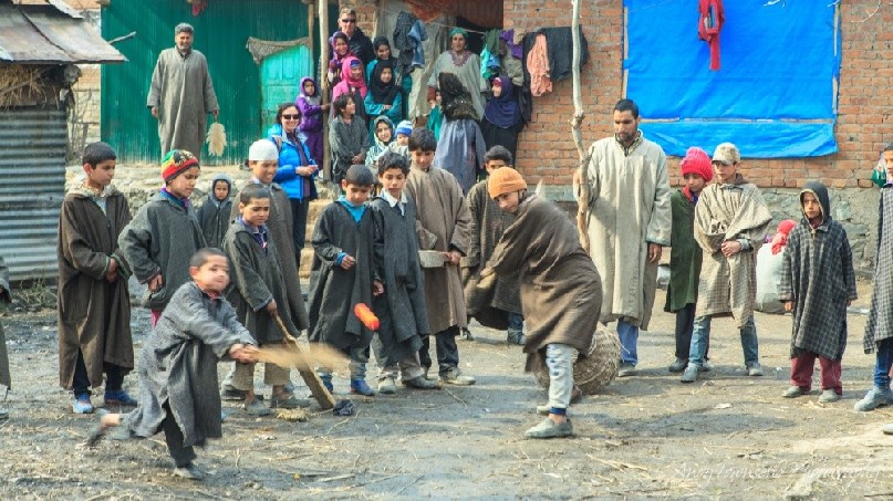 A group of boys line up to hit the ball in a game of backyard cricket.