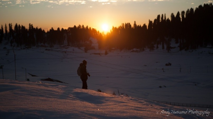 Early morning sun catches a photographer in the snow.