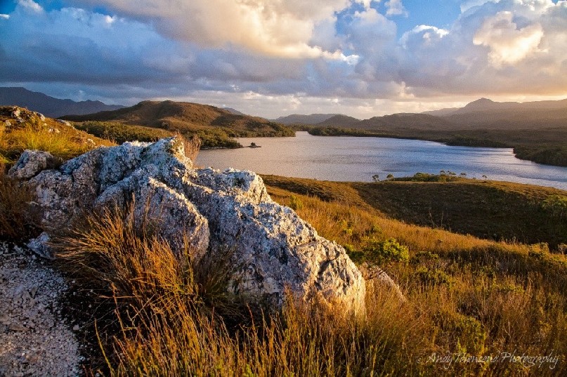 The sun sets over granite boulders in remote Bathurst Harbour in Southwest National Park, Tasmania.