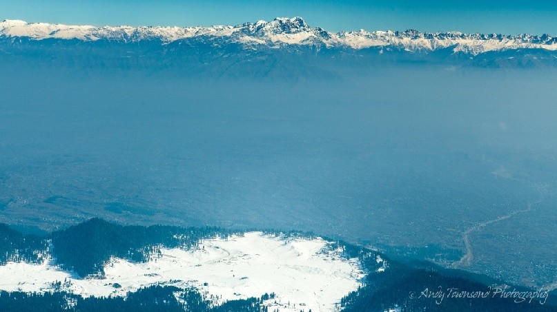 View from Mt Apharwat down the valley towards Gulmarg village with a layer of smog and fog sitting below distant mountains.