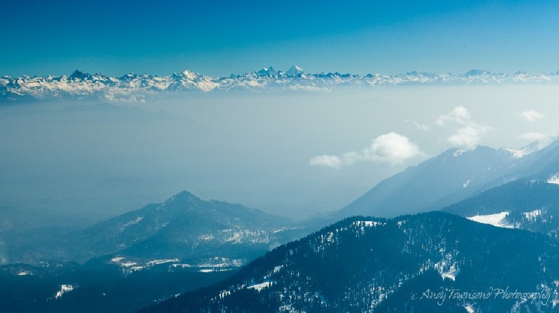 View from Mt Apharwat down the valley with a layer of smog and fog sitting below distant mountains.