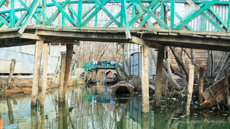An old bridge connects small islands of land in Dal Lake.
