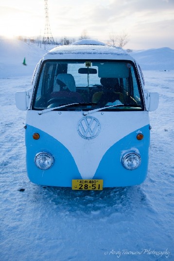 A small Japanese combi-styled van sits in an open snowy carpark