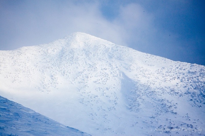 The clouds clear to show the northern side of the snowy peak of Mount Niseko-Annupuri